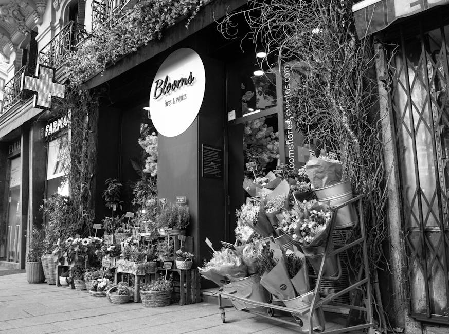 The exterior of Flowers Marylebone shop features a display of fresh floral arrangements arranged on wooden crates and in buckets, showcasing a variety of flowers including daisies, roses, and carnatio